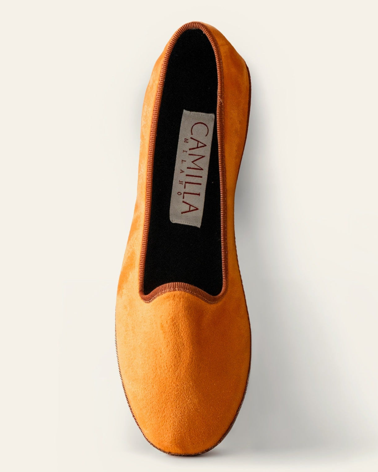 Orange slip-on shoe with 'Camilla' branding on a light gray background