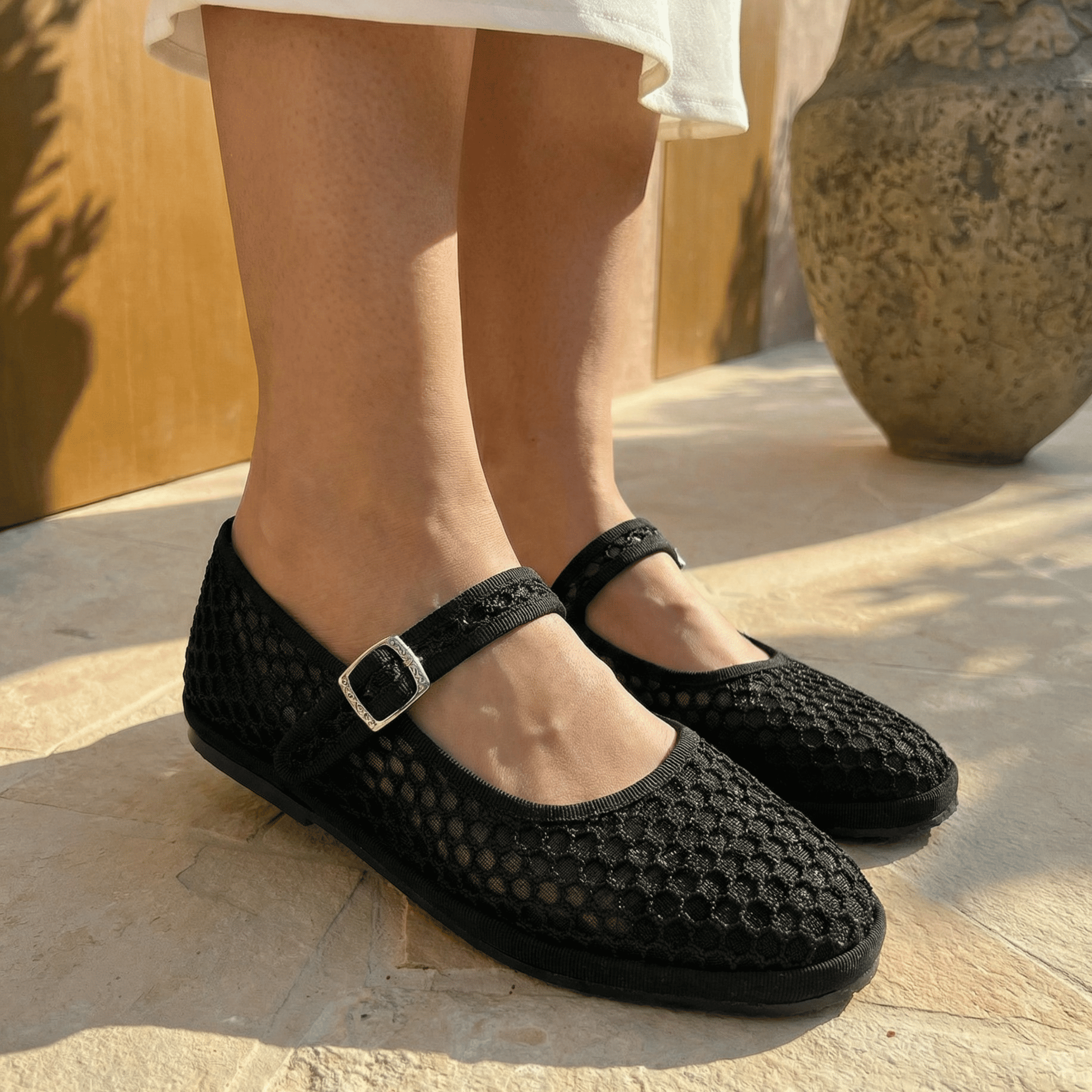 Black mesh shoes worn by a person on a stone surface
